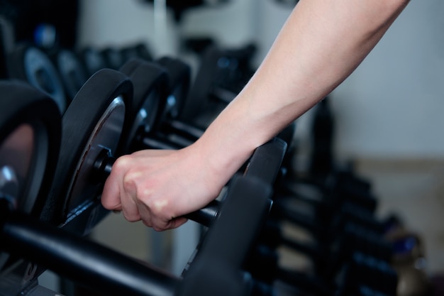 Main de l'homme, prenant des haltères dans la salle de gym