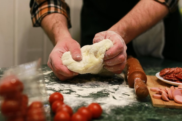 La main de l'homme prépare la garniture de pâte à pizza