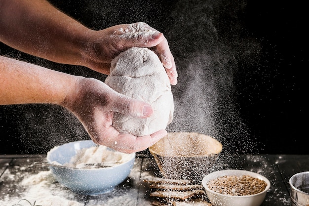 La main de l'homme prépare la pâte avec des ingrédients sur la table