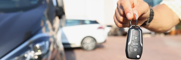 Photo la main d'un homme près de la voiture est titulaire d'une clé électronique gros plan système d'alarme flou sécurité des transports