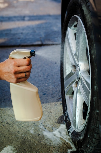 Photo main d'homme pulvérisant une roue de voiture