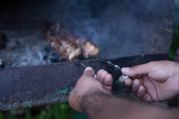 La main de l'homme redresse le barbecue