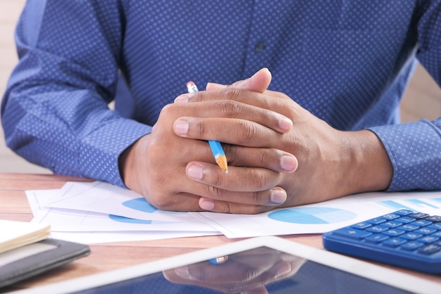 Main d'homme réfléchie avec un stylo sur papier financier