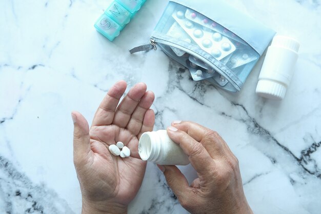 Main de l'homme senior avec des médicaments renversés hors de la vue de dessus du contenant de pilules