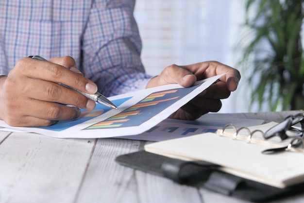 Main de l'homme avec un stylo analyse graphique à barres sur papier sur le bureau