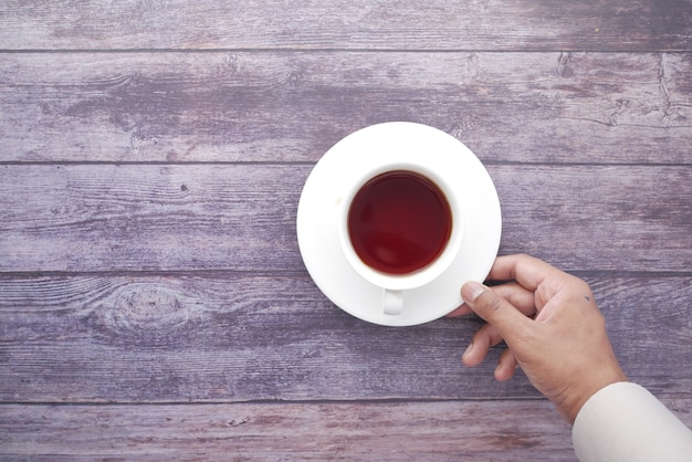 Main de l'homme avec une tasse de thé vert sur la table