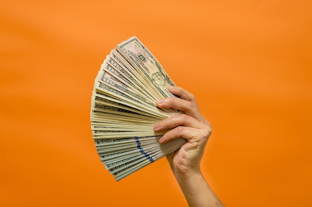 La main de l'homme tenant de l'argent en monnaie isolé sur fond orange