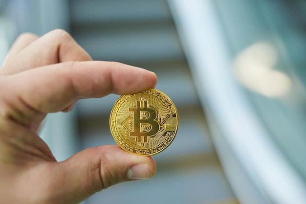 La main de l'homme tenant le bitcoin doré