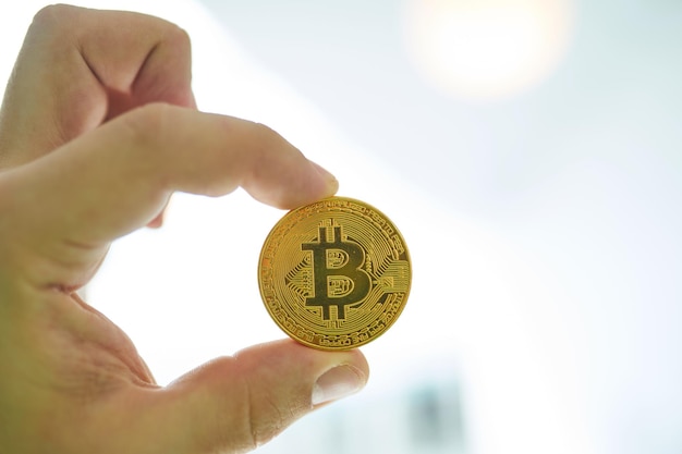 La main de l'homme tenant le bitcoin doré