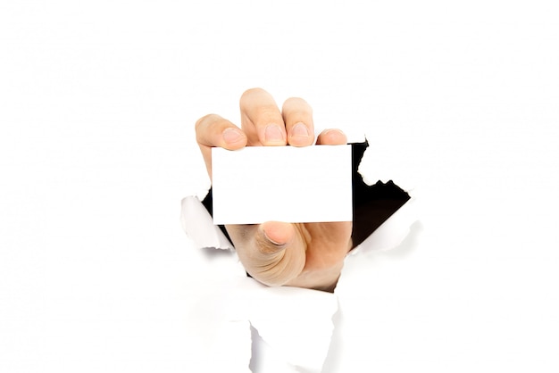 Photo main d'homme tenant une carte de visite blanche à travers un trou dans le mur ou du papier blanc cassé.