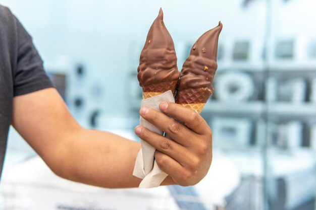 La main d'un homme tenant deux crêpes glacées recouvertes de chocolat