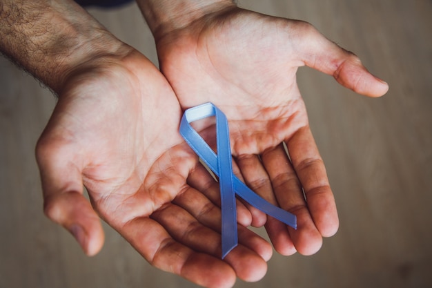 Main de l'homme tenant un ruban bleu. Mois de sensibilisation au cancer de la prostate