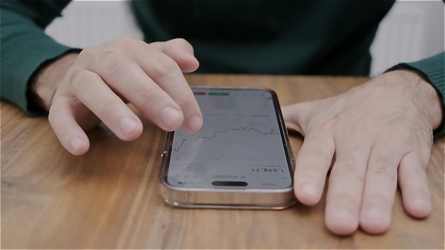 Main d'homme tenant un smartphone avec application de négociation d'actions en devises à l'écran Actions d'analyse financière