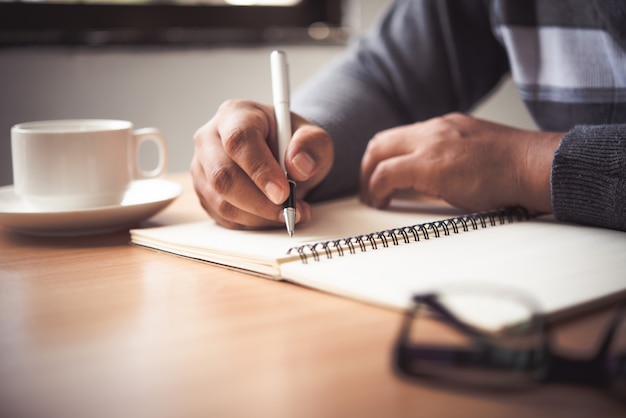 La Main D'un Homme Tenant Un Stylo Et Prenant Des Notes Dans Un Cahier.