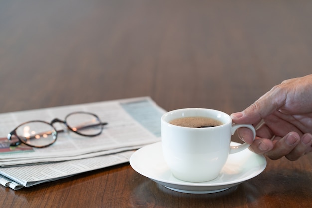 Main d'homme tenant une tasse de café chaud le matin