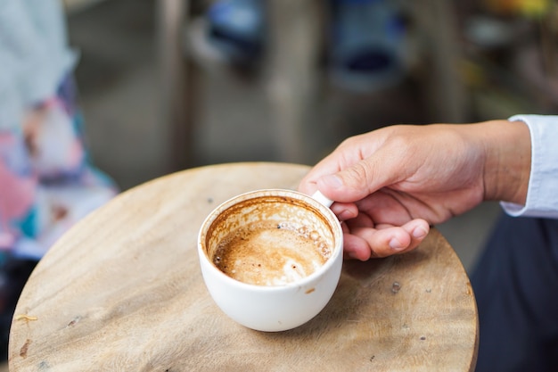 Main de l&#39;homme tenant la tasse à café Latte Art sur la table en bois