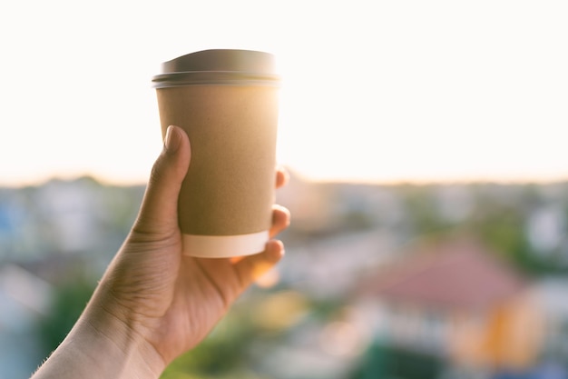 La main d'un homme tenant une tasse de café le matin sur le balcon