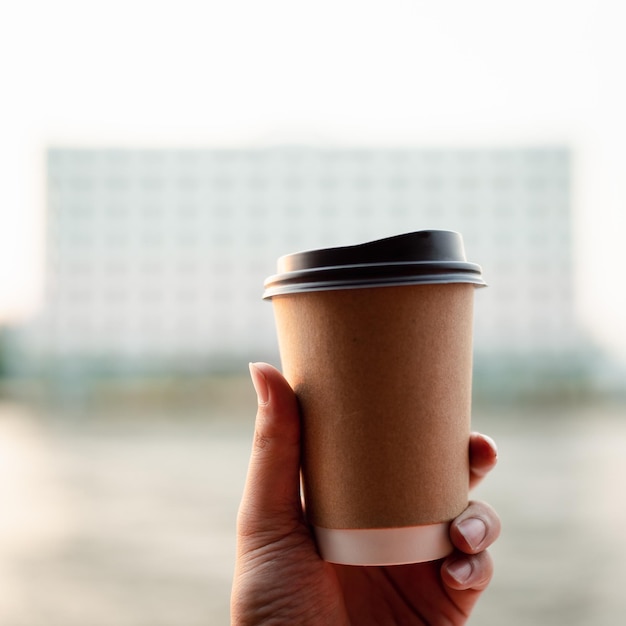 La main d'un homme tenant une tasse de café le matin avec rivière