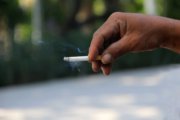 Une main d&#39;homme tient une cigarette qui brûle