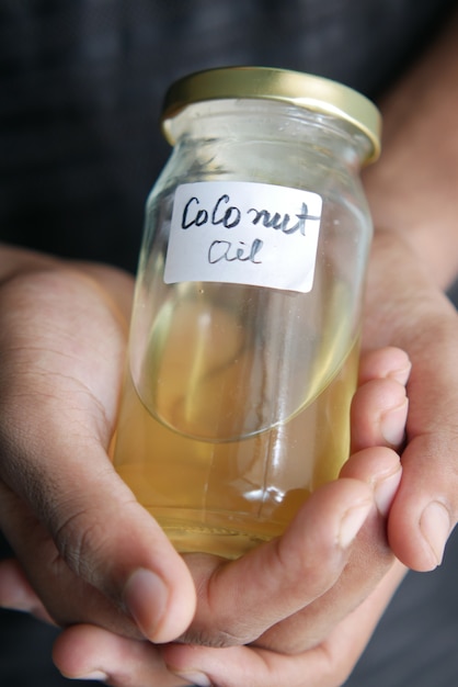 La main de l'homme tient un pot d'huile de noix de coco