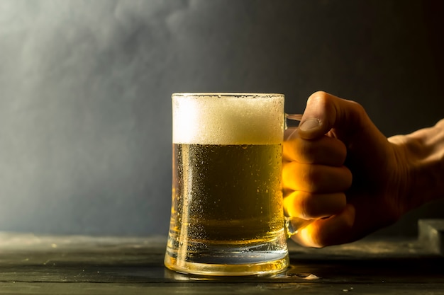 La main d&#39;un homme tient une tasse de bière fraîche