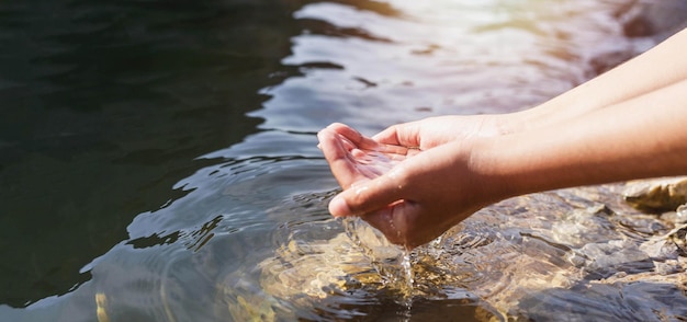 La main de l'homme touchant l'eau au milieu de la nature