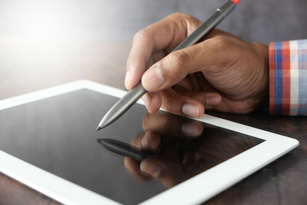 La main de l'homme travaillant sur une tablette numérique avec un stylo graphique