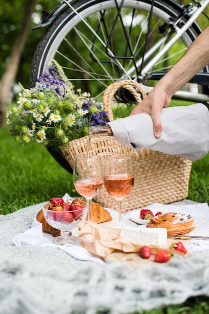 La main de l'homme versant du vin rosé dans des verres pique-nique d'été