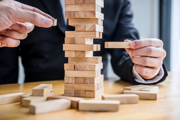 main d&#39;hommes d&#39;affaires plaçant et tirant des blocs de bois sur la tour