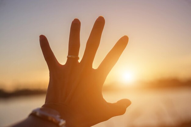 Photo la main humaine contre le ciel au coucher du soleil