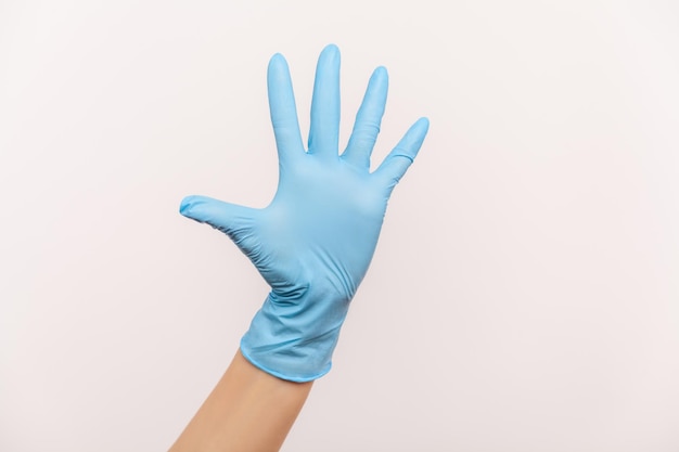 Main humaine dans des gants chirurgicaux bleus montrant le numéro cinq avec la main ou agitant la main pour saluer.