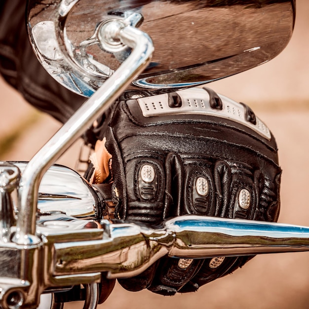 La main humaine dans des gants de course de moto tient une commande d'accélérateur de moto. Protection des mains contre les chutes et les accidents.
