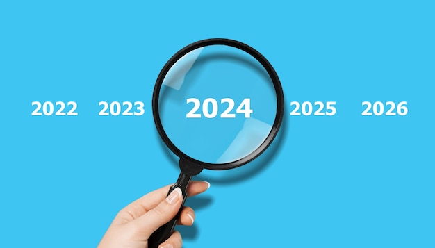 La main humaine avec une loupe et les chiffres 2024