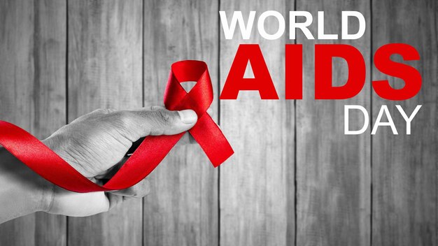 Main humaine montrant le concept de sensibilisation au ruban rouge Journée mondiale du sida
