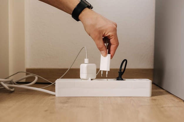 Photo la main humaine place le chargeur dans une rallonge remplie connecteur de câble blanc gros plan routine d'accueil