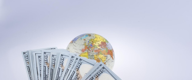 Photo main humaine tenant des billets en dollars américains à côté d'un globe modèle