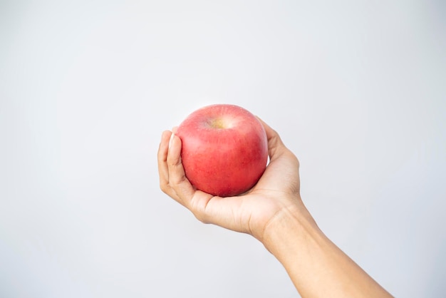 Une main humaine tenant une pomme avec un fond blanc