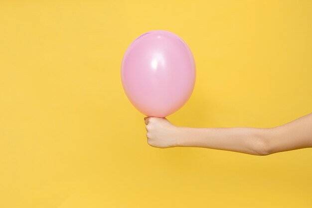 Photo la main humaine tient un ballon rose. couleur pastel