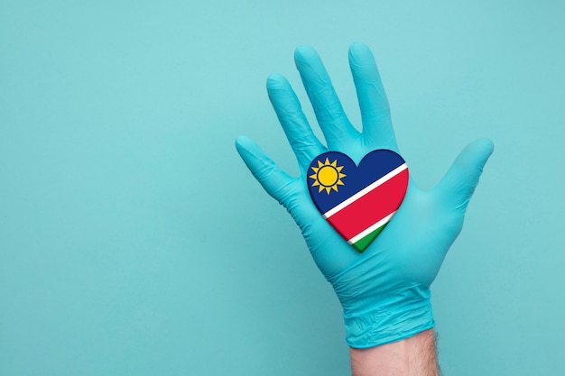 Main d'infirmière de coeur de santé médicale de la Namibie tenant le drapeau de coeur de pays