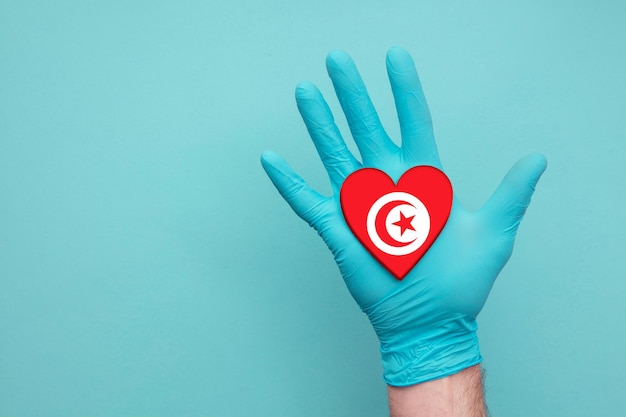 Main d'infirmière de coeur de santé médicale de Tunisie tenant le drapeau de coeur de pays