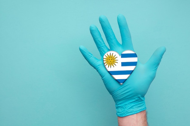 Main d'infirmière de coeur de santé médicale de l'Uruguay tenant le drapeau de coeur de pays
