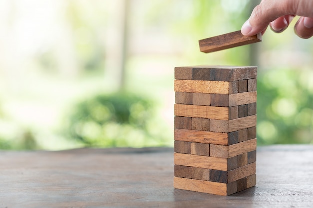 Main d&#39;ingénieur jouant à un jeu de blocs en bois sur bois