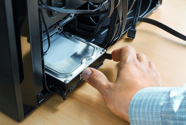 La main insère la mémoire du disque dur dans l'unité centrale de l'ordinateur