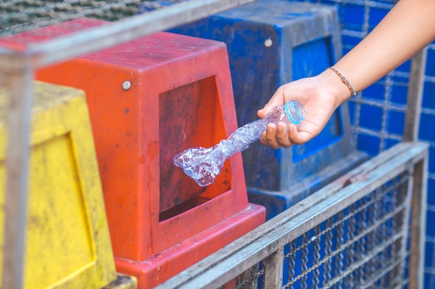 La main jette une bouteille en plastique dans le bac