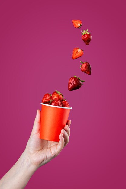 La main jette des fraises mûres