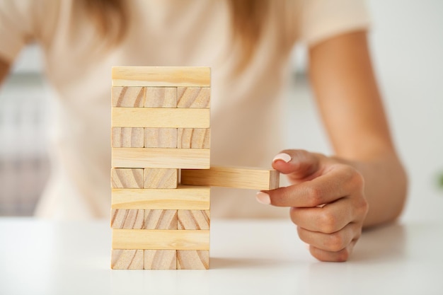 Main d'une jeune femme d'affaires pour jouer au jeu de blocs de bois avec stratégie et gestion de projet systématique d'entreprise