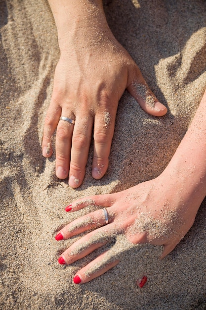 Main d'une jeune femme et d'un homme sur fond de sable Lune de miel sur la plage de l'océan