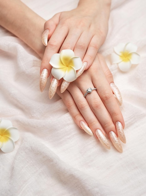 La main d'une jeune femme avec une manucure en perles blanches