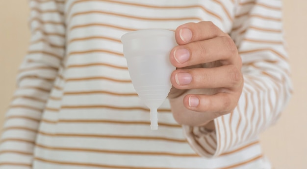 Main de jeune femme tenant une coupe menstruelle Mise au point sélective