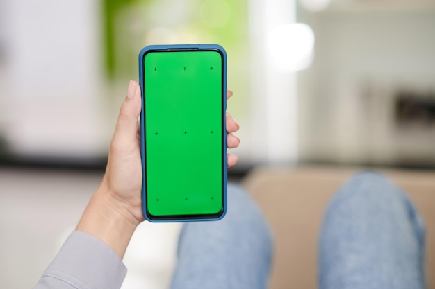 Main de jeune femme tenant un smartphone avec écran vert noir